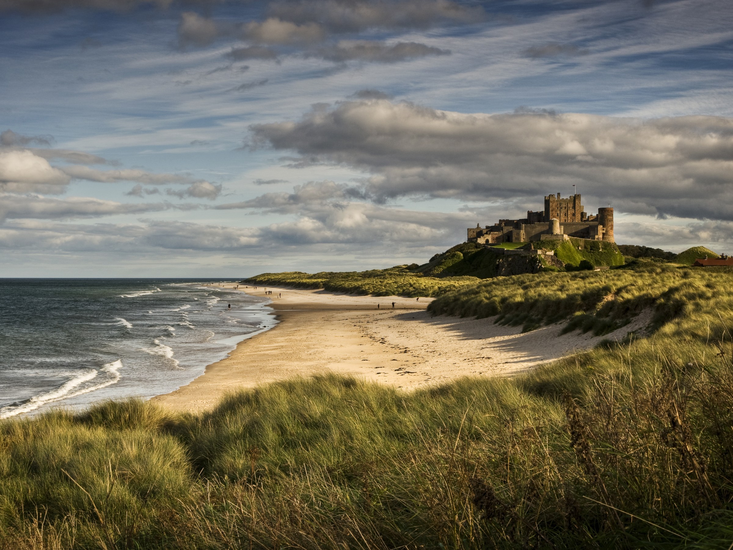 Late afternoon light illuminates the castle and beach at Bamburgh