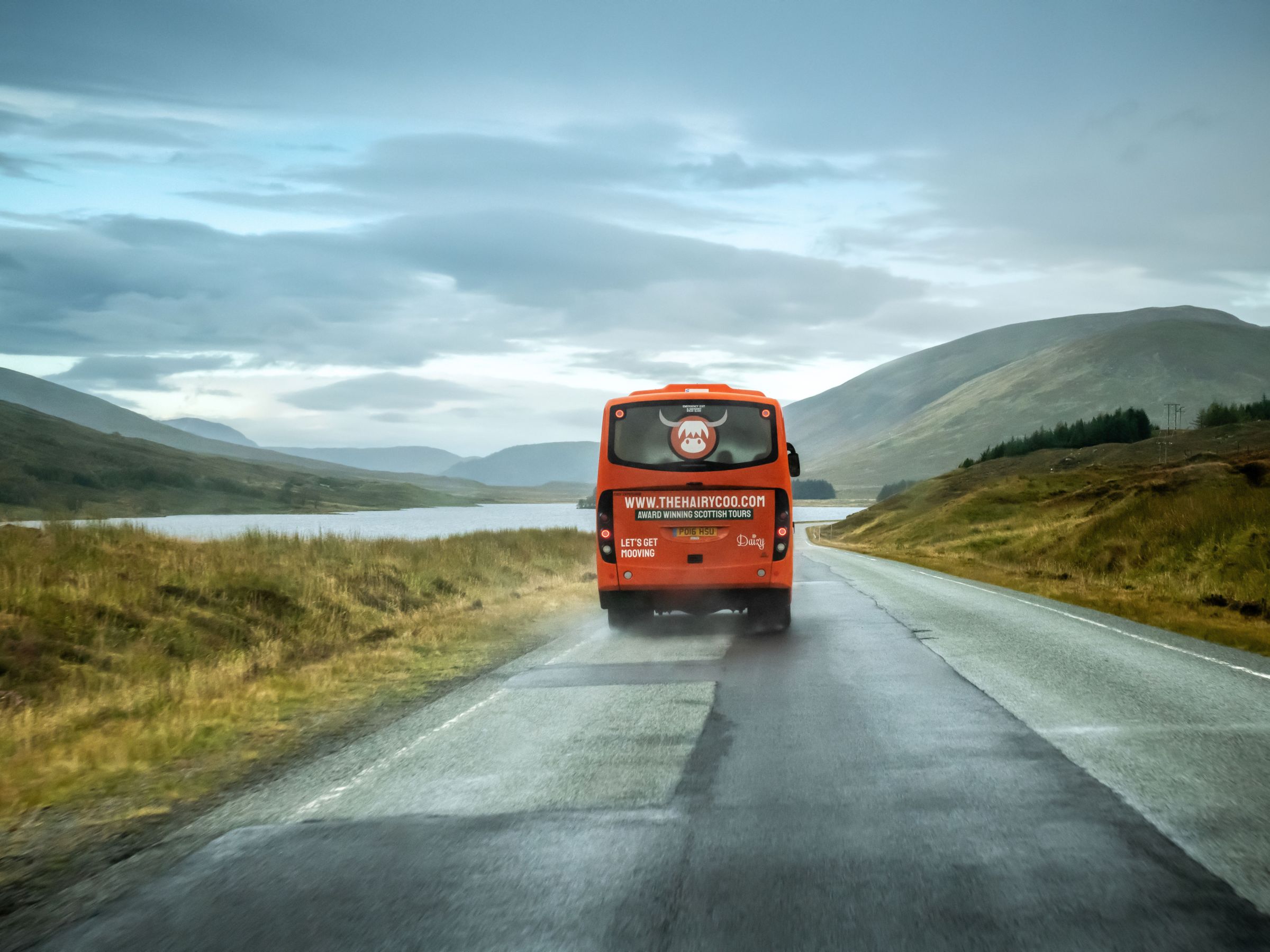 The Hairy Coo tour bus traveling through rural Scotland